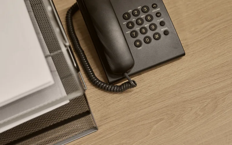 A desk telephone beside paper files in an office