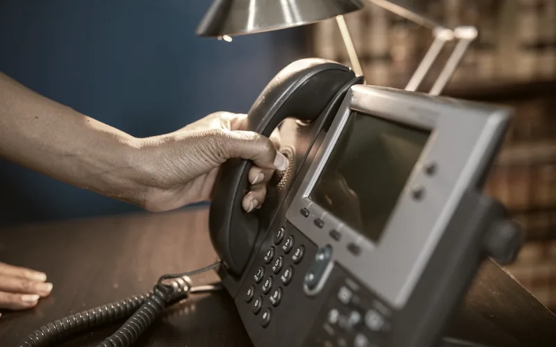 A telephone handset resting on a desk in low light